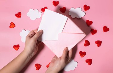 Sevgililer günü ya da anneler günü için içi kalplerle dolu bir zarfın üzerinde boş bir mektup tutuyordu. Model