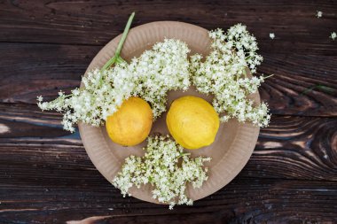 Environmentally friendly drink. Ingredients for a refreshing drink of elderberry and lemon on an ecological plate of recycled paper