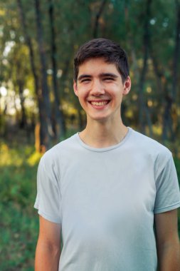 The boy is leaning to one side. The young man smiles. Man walking in the forest at sunset.