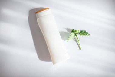 Shampoo with nettle tincture. Cosmetic bottle, shampoo dispenser product package. Plastic bottle mockup on a white background with trendy shadows. Fresh young nettles