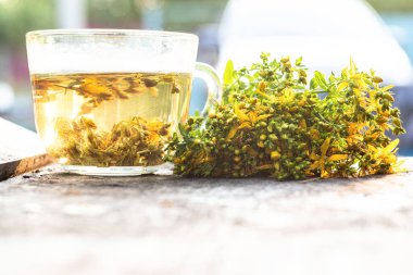 St. John otundan taze çiçek açmış bir demet taze otla St. John 's Wort tentürünün yanında. St. John otuyla şeffaf denetleyici.