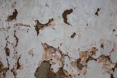 The old white cracked wall of clay houses with peeling paint