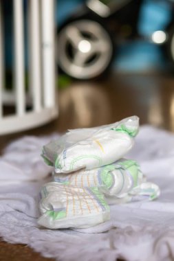 A bunch of dirty used diapers on the floor near the crib. Discarded diapers without a bucket in the nursery.