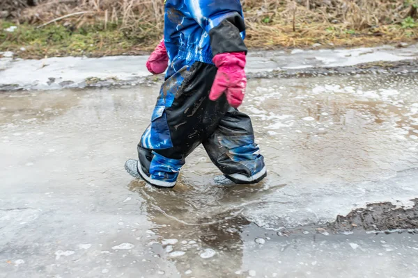 Small Child Walks Dirty Puddle Rubber Boots Spring Pieces Ice — Zdjęcie stockowe