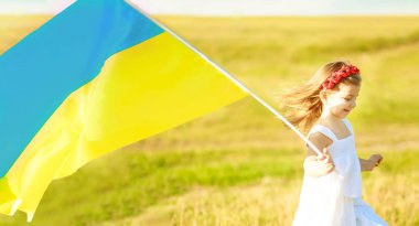 Ukrayna 'nın mavi-sarı bayrağı Ukrayna' nın bağımsızlık gününde Ukraynalı küçük bir kızın ellerinde rüzgarda dalgalanıyor. Gülümseyen bir çocuğun ellerinde Ukrayna 'nın sembolleri. Yumuşak odak