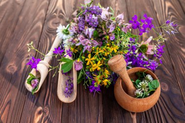 Summer medicinal herbs - St. John's wort, chamomile, clover near wooden mortar. Preparation of medicines from natural plants by herbalists