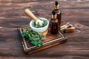 Lamium albüm, beyaz ısırgan otu çiçekleri havan topu. Şifalı bitkilerin şifalı bitkilerinden iksirlerin hazırlanması. Homeopatik ilaçlar için pipetle birlikte eczane şişesinde gerekli yağ.