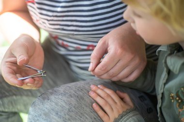 Annem çocukların tırnaklarını maşayla kesiyor. Çocuk bakımı. Kişisel temizlik..