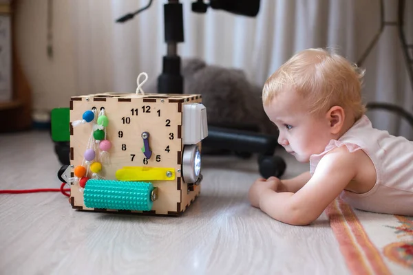 Activity Board. The baby learns the numbers on the clock on the bisiboard. Early development of children with a playful wooden cube toy Montessori.