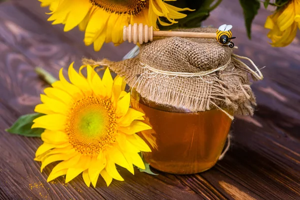 キャンバス蓋付きの透明な瓶の中の有機ひまわり蜂蜜と蜂蜜のためのスプーン 薬に使われる健康的な蜂蜜を集めるために栽培されたひまわり — ストック写真