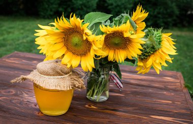 Organic sunflower honey in a transparent jar with a canvas lid and a spoon for honey. Sunflower grown to collect useful healthy honey used in medicine. Soft focus