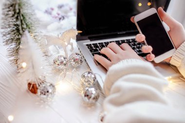 Noel alışverişi. Noel için dekore edilmiş bir masaüstü bilgisayarında akıllı telefondan veri seçmek ve girmek
