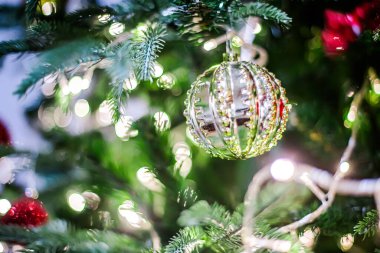 Bulanık yeşil bir arka planda, yılbaşı ağacının dallarında gümüş bir top..