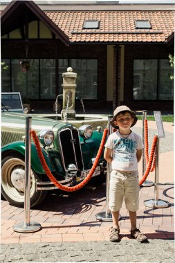 Khodoseevka Ukrayna - 07: 20 2016: Dampf Kraft Wagen. Eski arabaların sergisi. Çocuk eski bir arabanın çitli kopyasının yanında.