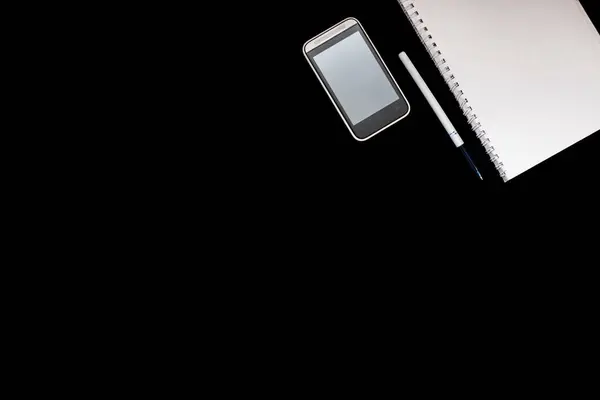 notebook on rings, mobile phone, pen, book and tablet on black background. Set for online training and Education and distance work. Flat lay. Top view.