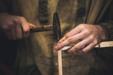 Adam arılar için çivi ahşap çerçeveyi tıkıyor. Uzun ince parmakları olan erkeklerin elleri ahşap çerçeveyi tutar..