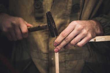 Adam arılar için çivi ahşap çerçeveyi tıkıyor. Uzun ince parmakları olan erkeklerin elleri ahşap çerçeveyi tutar..