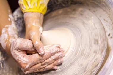 Çocuk çömlekçilik yolculuğuna başlarken öğretmenin becerikli rehberliği..