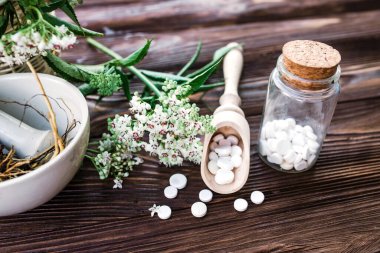 Valerian tablets with sedative properties. Pharmaceutical jar with pills on a wooden table. Cooking Valerian Root in a Mortar for Herbalism Elixirs. Soft focus