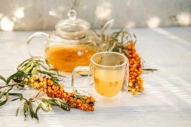 Temiz cam bir çaydanlıkta bulunan Aromatik deniz dikenli çay, canlı renginde organik deniz dikenli çay, sağlıklı bir seçim.