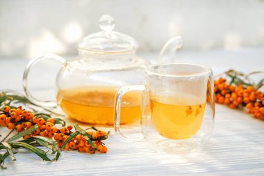 Deniz karabatağı çayının canlı renkleri şeffaf bir çaydanlığa yakalanmış. Deniz dikenli çay karışımında sonbaharın canlılık özü için homeopatik bir ilaç.