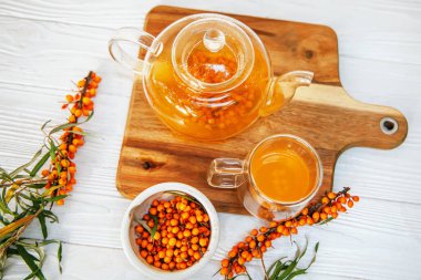 berrak bir çaydanlıkta demlenen deniz dikenli çay, lezzetli bir karışım. Taze deniz dikenli yaprak ve böğürtlenli çay zamanı.