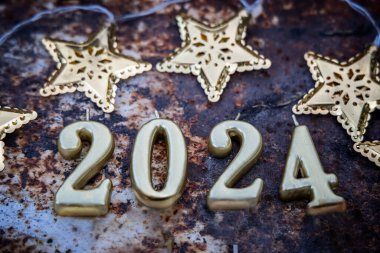 2024. Yeni yıl yaklaşıyor. Paslı arkaplanda altın yıldızlı numaralar