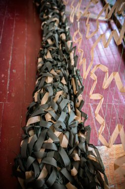 Makro görünüm, iyi örülmüş kamuflaj ağı malzemesinin ustalığını gözler önüne seriyor. Kamuflaj ağının bitmiş kısmı yerde yatıyor.