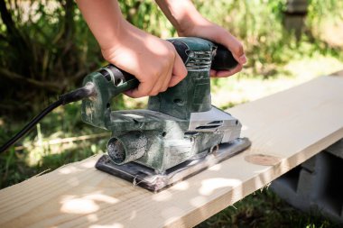 Elektrikli el planörü gibi talaş da uçar. Bir zanaatkarın elindeki çiğ odunu elektrik planörüne dönüştürür.