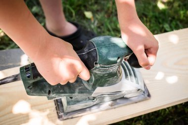 Elektrikli planlama makinesi olan detaylı ahşap işçiliği cilalı bir görünüm için elektrikli planlamacı bir zanaatkarın elinde.