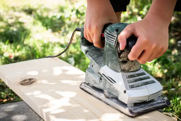 Electric Planer in Action . craftsman smoothing rough wood using an electric planing tool. Electric Planer in Action