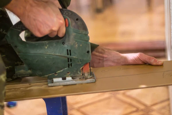 carpenter using an electric jigsaw to create a new piece of furniture from recycled materials. The carpenter is using the jigsaw to cut the materials into shape, and the resulting piece is a