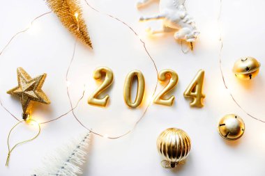 Tatil geçmişi. Mutlu yıllar 2024. Noel süslemeleri, topları ve tek boynuzlu atı olan beyaz bir arka planda 2024 rakamları..