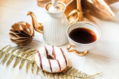 Kraft kağıdından yapılmış Noel ağacı oyuncakları. Beyaz bir masada çay partisi, çaydanlık ve çörekle kahve fincanı.