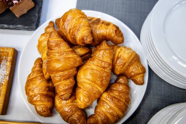 Masadaki beyaz tabakta taze kruvasan.