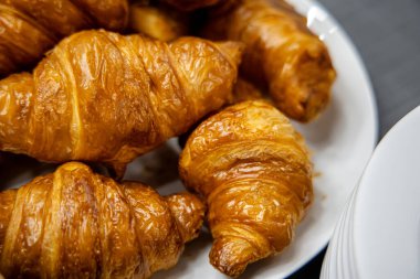 Masadaki beyaz tabakta taze kruvasan.