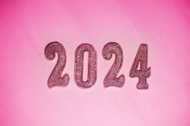 2024 Yeni Yıl. Pembe arka planda gelecek yeni yılın numaraları. Giden yılın moda rengi bir moda oyuncağı tarzında...