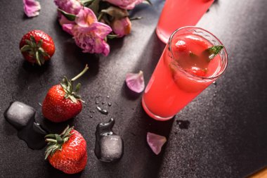 Böğürtlenli çilekli mojito. Klasik kokteylde tropik bir dönüş. Taze çilekler, kireç ve nane yaprakları birleşerek canlı ve lezzetli içecekler oluştururlar. Koyu arkaplanda buzun üzerinde servis edilir.