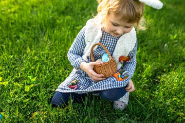Küçük kız Paskalya günü bahar bahçesinde yumurta arıyor. Geleneksel Paskalya kutlaması.