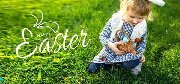 stock image little girl hunts for an egg in a spring garden on Easter day. Traditional outdoor Easter celebration.