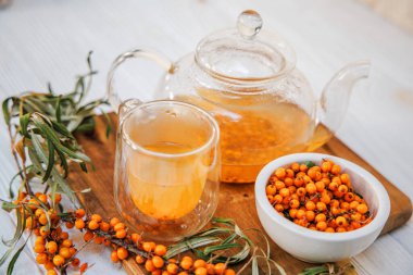 Temiz cam bir çaydanlıkta bulunan Aromatik deniz dikenli çay, canlı renginde organik deniz dikenli çay, sağlıklı bir seçim.