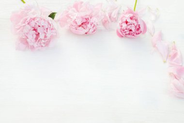 Pembe şakayık çiçekleri, özenle düzenlenmiş, temiz beyaz masada kompozisyon için doğal cazibe. Kopyalama alanı olan üst görünüm. Metnin için boş yer. Düğün ya da Sevgililer Günü konsepti