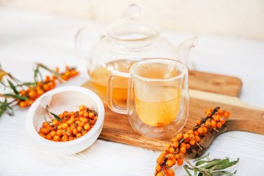 Deniz dikenli çay ile cam bardak ve çaydanlık, aroma karışımı ve sağlık sigortası, lezzetli ve tıbbi içecek..