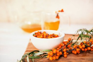 Taze toplanmış deniz dikenli üzümler beyaz tabakta ve kesme tahtasındaki deniz dikenli dallar..