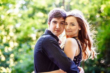 Gülümseyen mutlu kız, bahar parkındaki yakışıklı adamın kollarında..