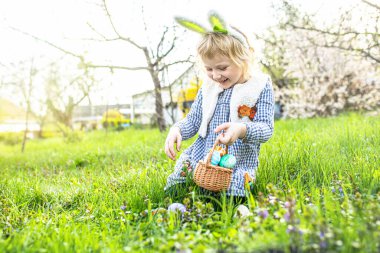 Paskalya yumurtası avında neşeli çocuklar sepetinde rengarenk hazineler topluyor bahar neşesinin ortasında.