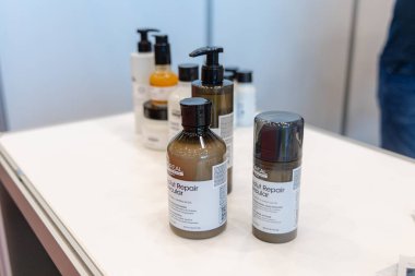 Osijek, Hırvatistan - 7 Haziran 2024: Sağlık ve Güzellik Fuarı. Bir fuarda beyaz bir masada sergilenen iki şişe ve bir kutu LOreal Cilt Tamir Ürünleri. Şişeler koyu kahverengi camdan yapılmış ve siyah pompaları var..