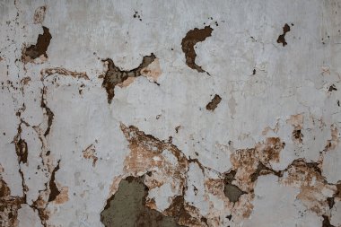 The old white cracked wall of clay houses with peeling paint