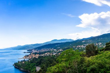 Hırvatistan 'ın Opatija kıyı şeridinin manzarası 27 Mayıs 2024' te çekildi. Resim, mavi suları, yemyeşil tepeleri ve dağların arasına kurulmuş uzak bir kasabayı resmediyor..