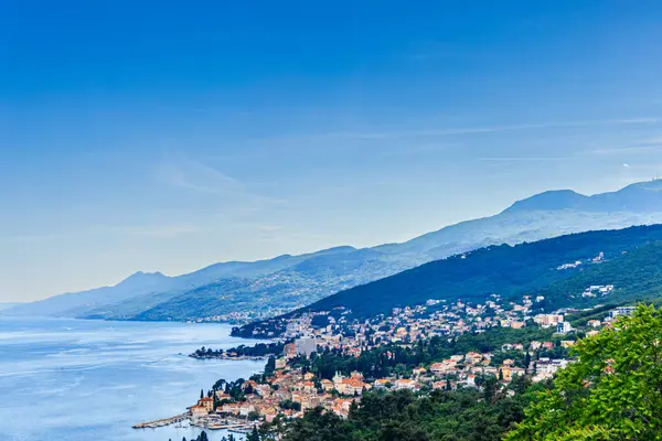 Hırvatistan 'ın Opatija kentinin panoramik bir manzarası, Adriyatik Denizi ile gür, ormanlı dağ sıraları arasında yuva yapmış kasabayı gösteriyor.